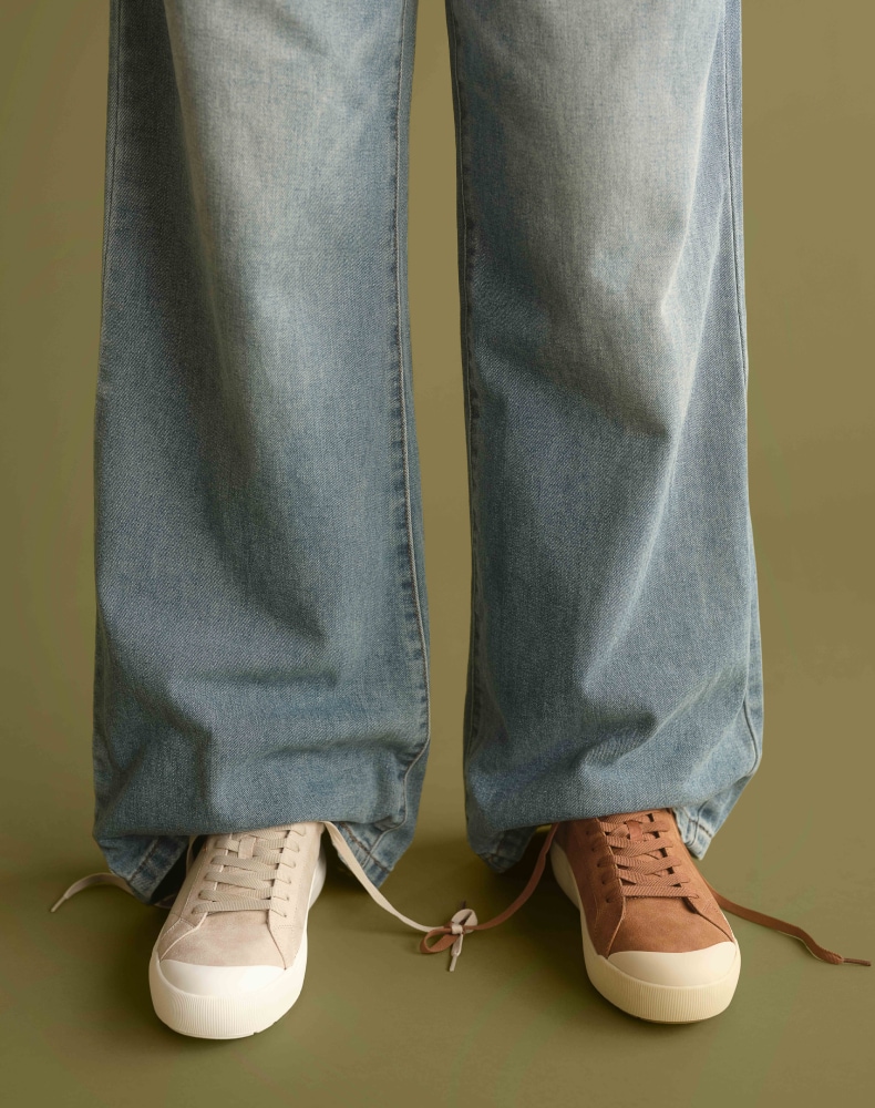 a woman wearing mismatched pairs of the time off sneaker with baggy jeans
