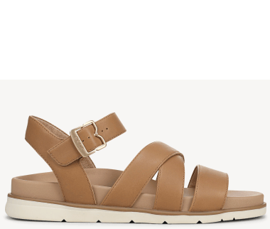 Side view of a women's flat strappy sandal in tan with an off-white sole. 